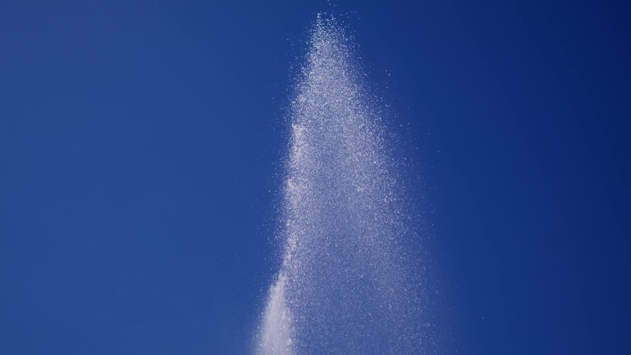 Water shoots upward against bright blue sky. Clear, sparkling spray arcs gracefully. Ideal for summer, travel, or refreshing themes. Perfect for advertising, tourism, or nature content