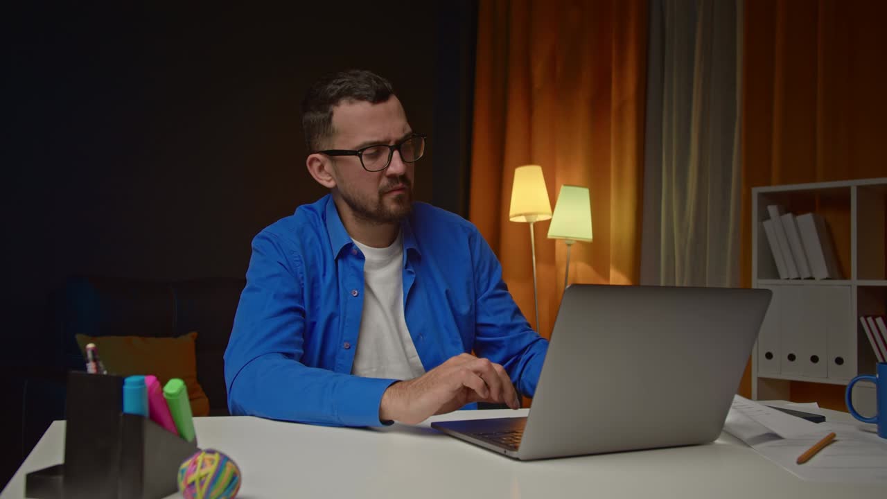 joven serio sentado en el escritorio en la oficina de casa tomando notas trabajando remotamente. freelance usando portátil para trabajar desde casa preparando un informe