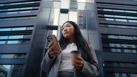 Low-Angle-Ansicht-Einer-Geschäftschinesin,-Die-Auf-Der-Straße-In-Der-Stadt-Steht-Und-Eine-SMS-Schreibt