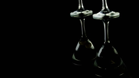 papel gris quemando sobre las aceitunas en dos copas de cóctel contra un fondo negro