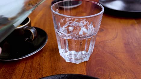 water being poured into a glass on a table