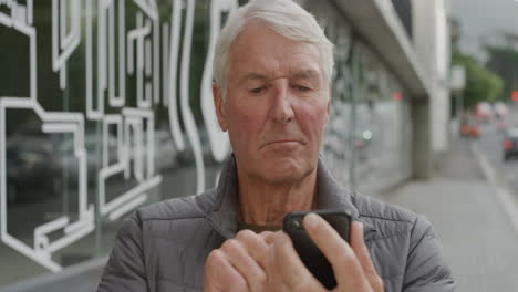 portrait of midde aged caucasian man using smartphone texting browsing online sending sms message on mobile phone technology app on urban city street