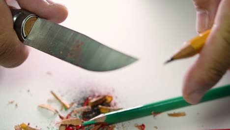 Footage-of-hands-slowly-sharpening-a-pencil-and-some-coloured-pencils-with-a-sharp-knife