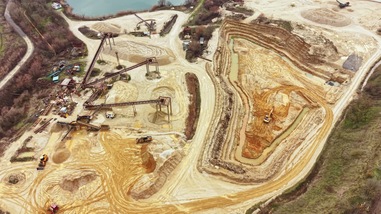 Construction site shows activity and machinery involved in excavation and land clearing for development near a water body during daylight hours