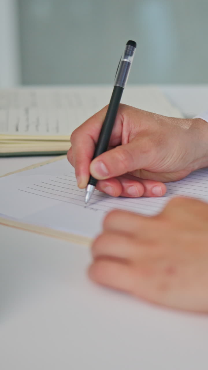 Primo piano di una mano che scrive su carta con una penna