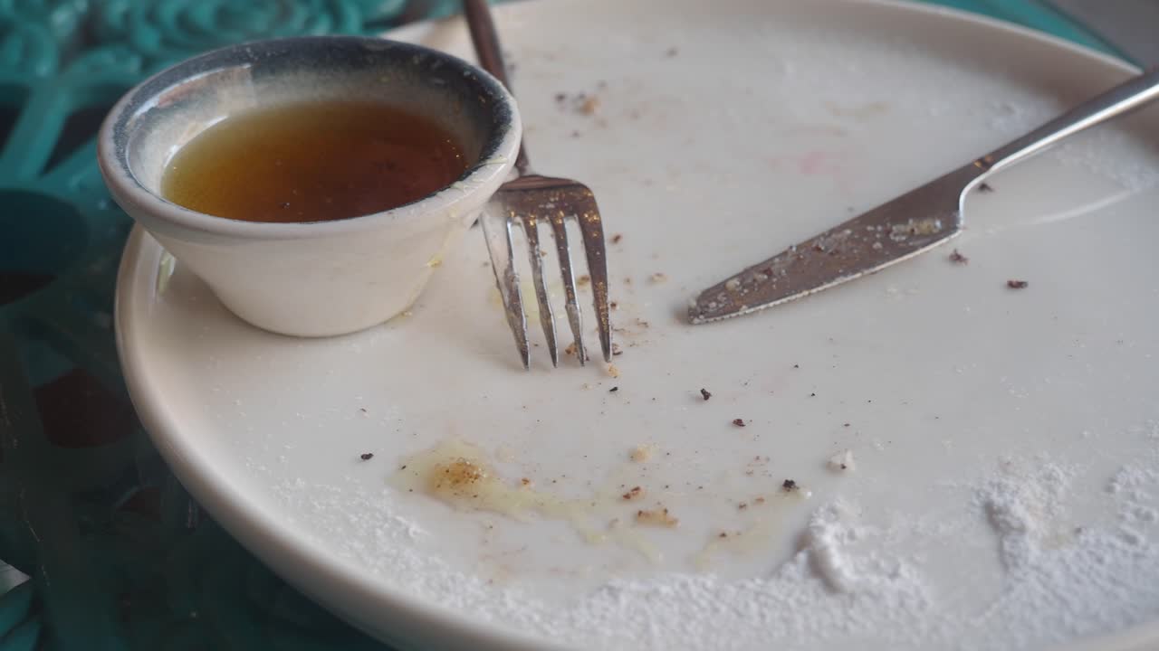 Dirty Plate with Leftover Crumbs, Fork, Knife, and Syrup After a Meal