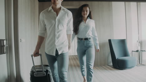 young couple going along corridor with baggage. cute couple holding hands.