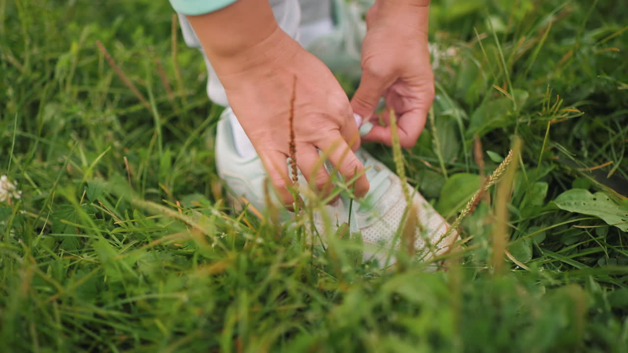 Elegant coach with neat hands crossing white sneaker robe on fresh grassy environment outdoor preparing for activity showing healthy active lifestyle during sunny summer day focus on fitness