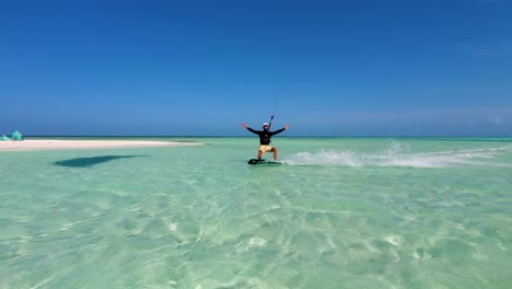 man enjoy kitesurf open arms tricks while sail on turquoise caribbean sea, los roques