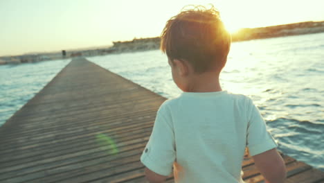 little boy running on the pier at sunset