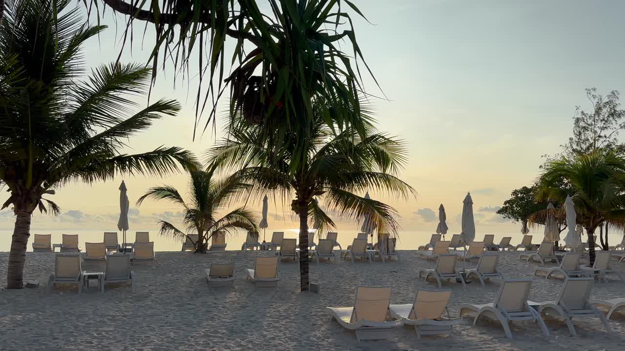 Lettini prendisole su una spiaggia a Zanzibar all'alba