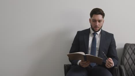 male candidate wearing suit in office checking notes before job interview 1