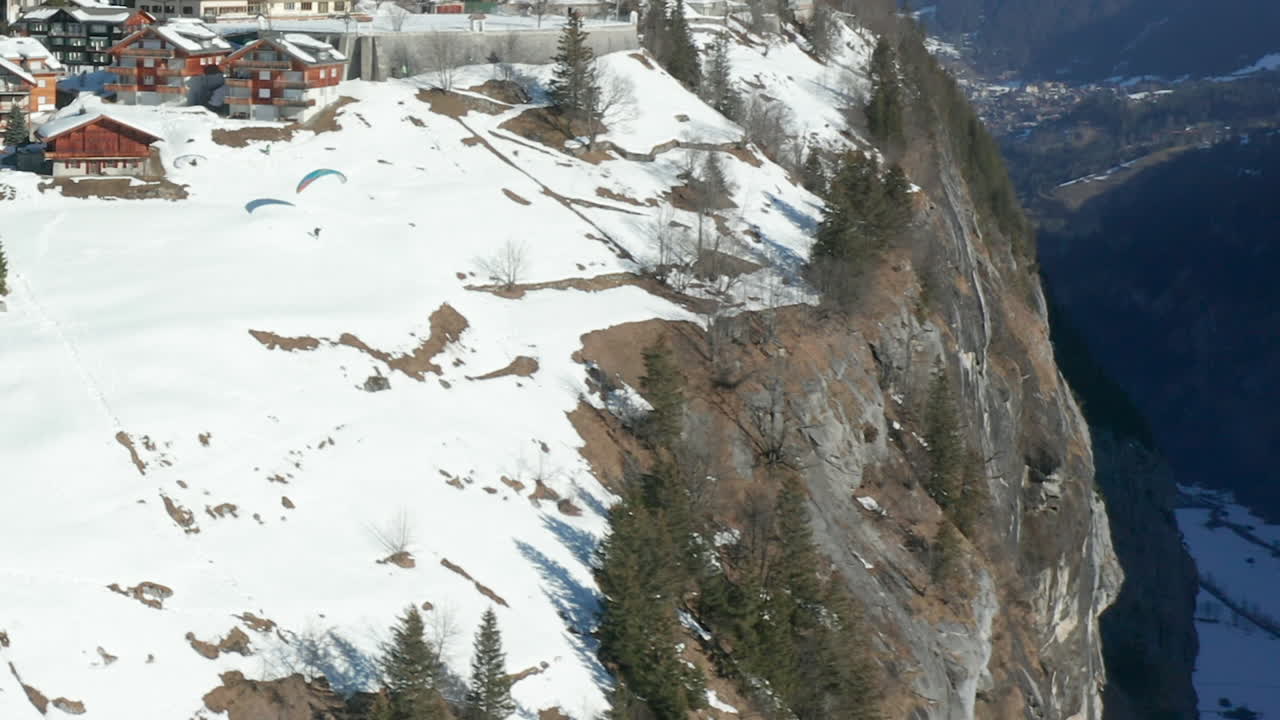 아름다운 스위스 마을 근처 산 가장자리에서 패러글라이더 점프의 공중 - hd 자르기