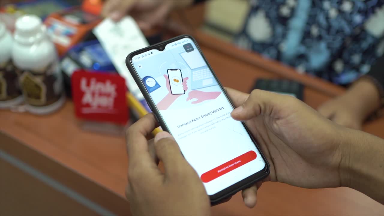 teléfono móvil en mano con interfaz de aplicación de pago que muestra un mensaje de pago exitoso con marca de verificación