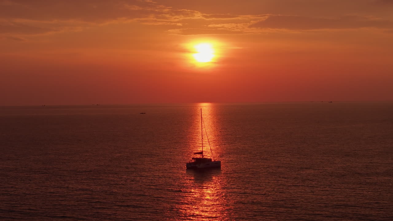 Sunset over the ocean with a sailboat