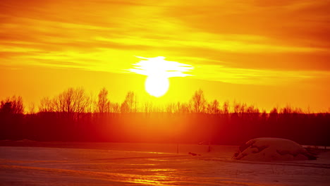 puesta de sol súper brillante sobre el paisaje rural de invierno y la silueta de la línea de árboles, lapso de tiempo de fusión