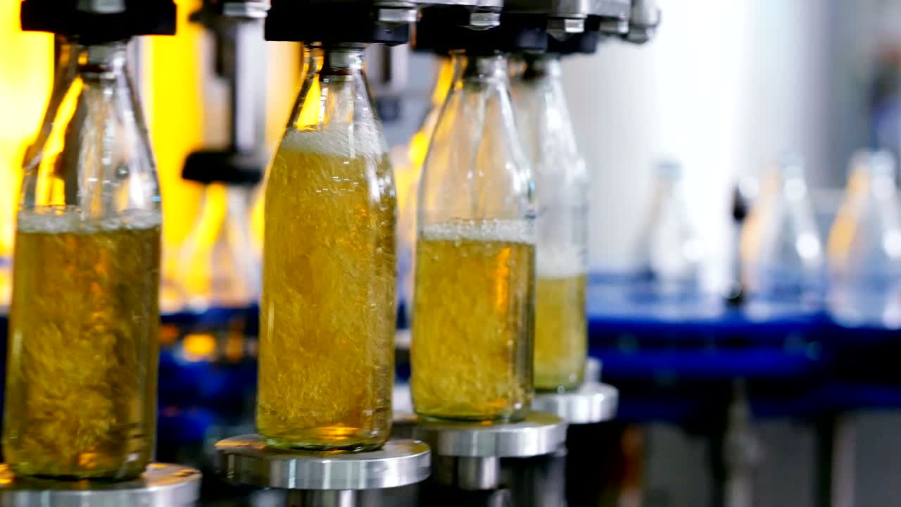 línea de máquina automática para llenar agua en una botella de vidrio. embotellado de bebidas a base de hierbas en botellas de vidrios. producción de agua potable y bebidas.