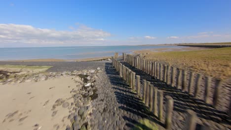 vuelo aéreo de drones a lo largo de olas de madera en una playa vacía a la luz del día