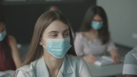 linda estudiante con mascarilla levanta la mano en clase