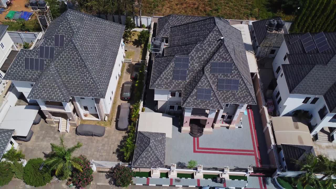 Krásný záběr zdvihem kamery na luxusní domy s fotovoltaickými solárními panely na střechách v nové předměstské čtvrti v Abuji, Nigérie.