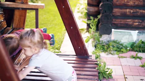 Close-up-Children-swing-on-a-large-wooden-swing-near-the-summer-house-they-play