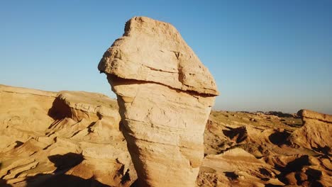 Fly-over-a-single-dust-erosion-cliff-rock-formation-in-desert-day-time-summer-season-tilt-shift-view-vibrant-panoramic-landscape-of-natural-wonderful-landform-middle-east-scenic-drone-shot-hot-climate