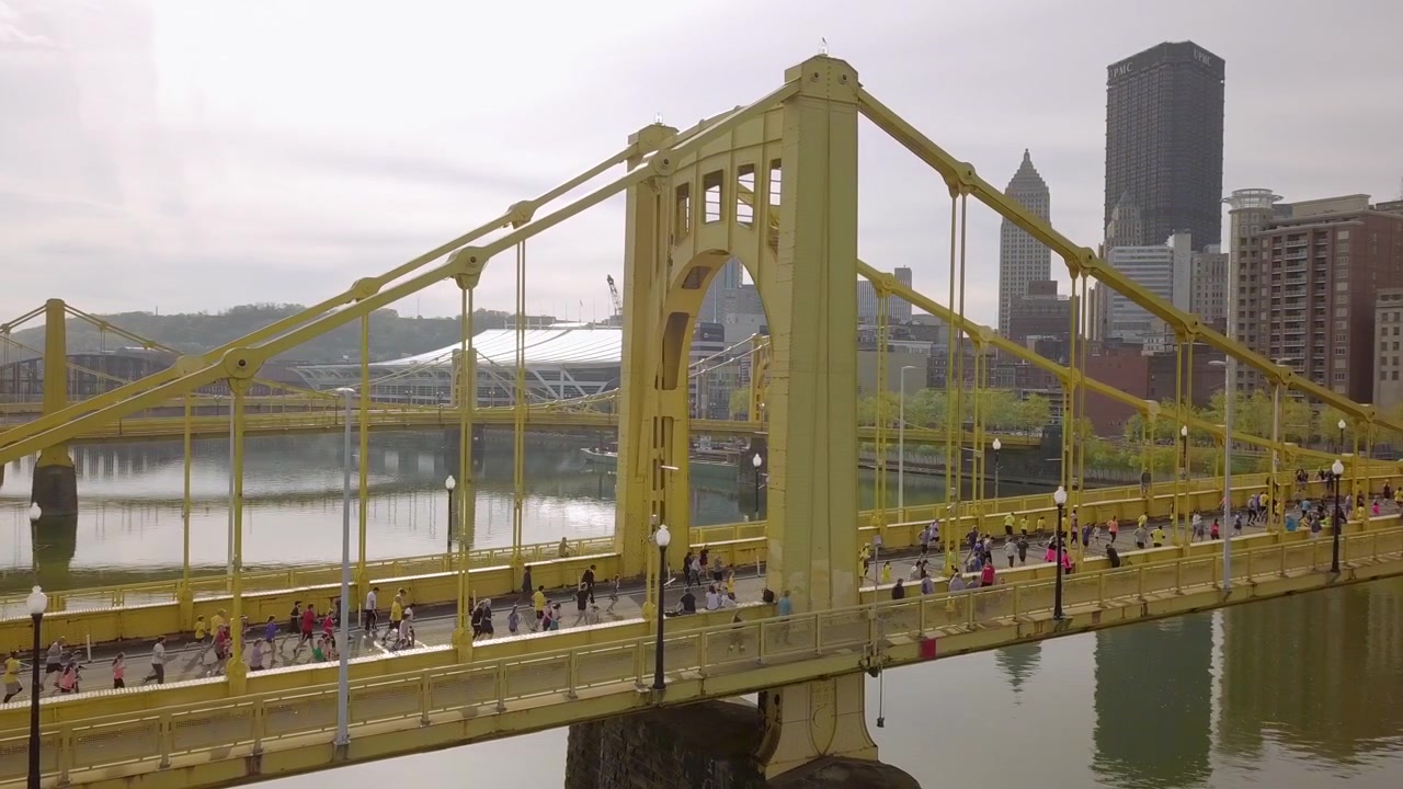 Ripresa aerea dall'alto con inquadratura a seguire di corridori che attraversano un ponte, Maratona di Pittsburgh.