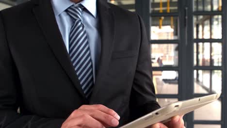 Businessman-using-tablet-and-smiling-at-the-camera