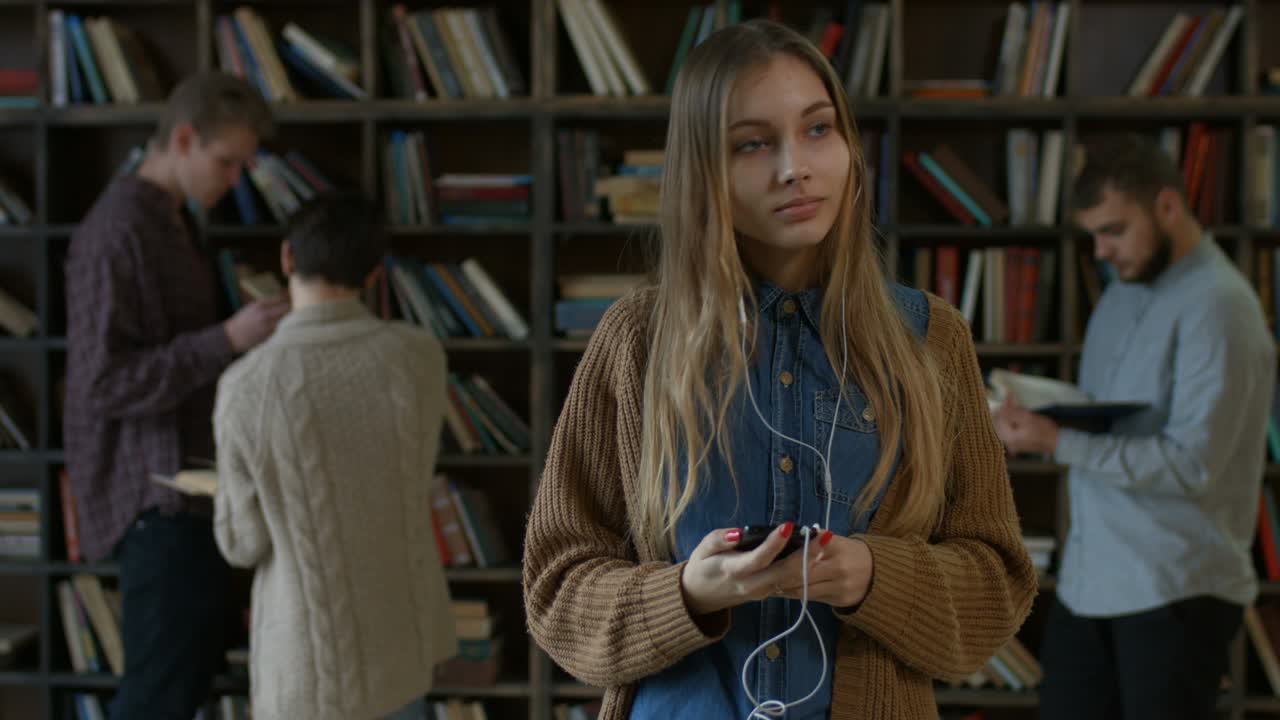 chica escuchando música con auriculares en la biblioteca