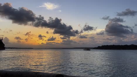 Toma-De-Paisaje-De-Una-Hermosa-Puesta-De-Sol-Tropical-Dorada-Con-Un-Barco-De-Transporte-En-La-Laguna-Guaraíras-Desde-El-Destino-Turístico-Tibau-Do-Sul-Brasil-Cerca-De-Pipa-En-Rio-Grande-Do-Norte-En-Una-Noche-De-Verano