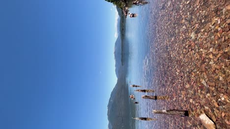 lago claro con orilla de guijarros y fondo de montaña en la patagonia argentina, día soleado y brillante