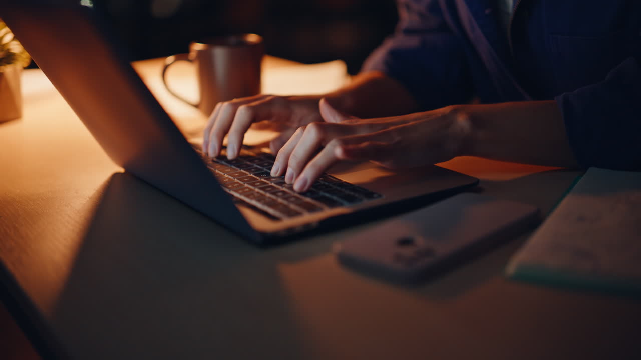 Vrouw schrijft 's nachts in appartement, close-up. Glimlachende freelancer typt op laptop