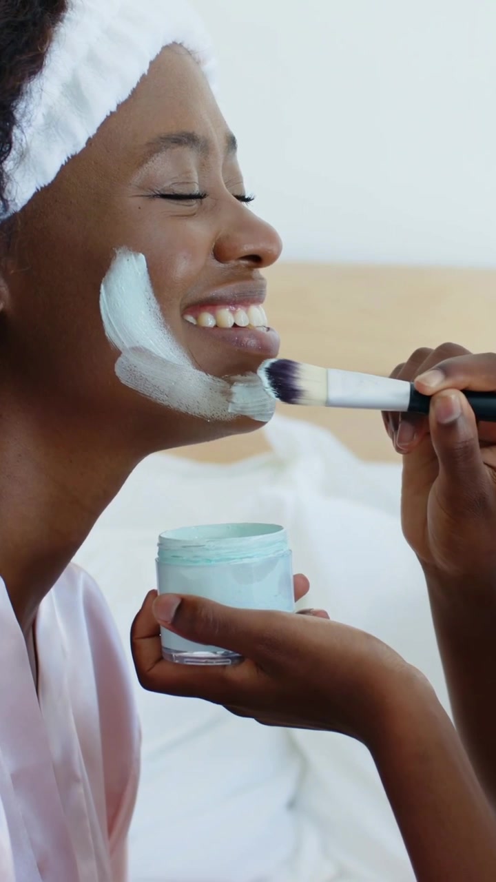 Vertical video: Dipping, child brushing cream on adult face in bed for care, jar robe, copy space