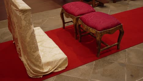 golden prayer bench and red cushioned stools arranged for wedding ceremony