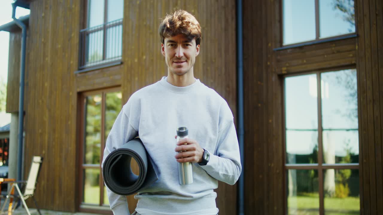 야외에서 요가 매트와 물 병을 가진 남자