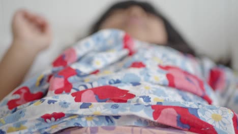 a young girl lying in bed, sleeping peacefully.