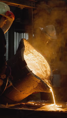 team of foundry workers pouring glowing molten iron from ladle into molds