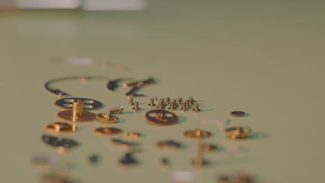 watchmaker picking up tiny screws together with other parts of mechanical watch on the table by tweezers