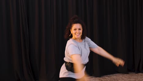 Curly-Woman-With-Bag-On-Waist-Dancing-In-The-Studio---zoom-shot