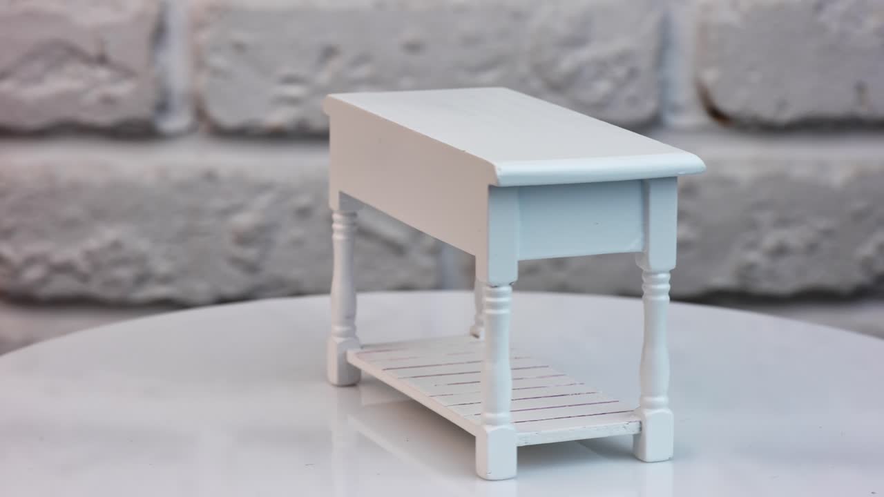 Toy table with three drawers on the turning table. White carved miniature table for a toy house interior. Close up.