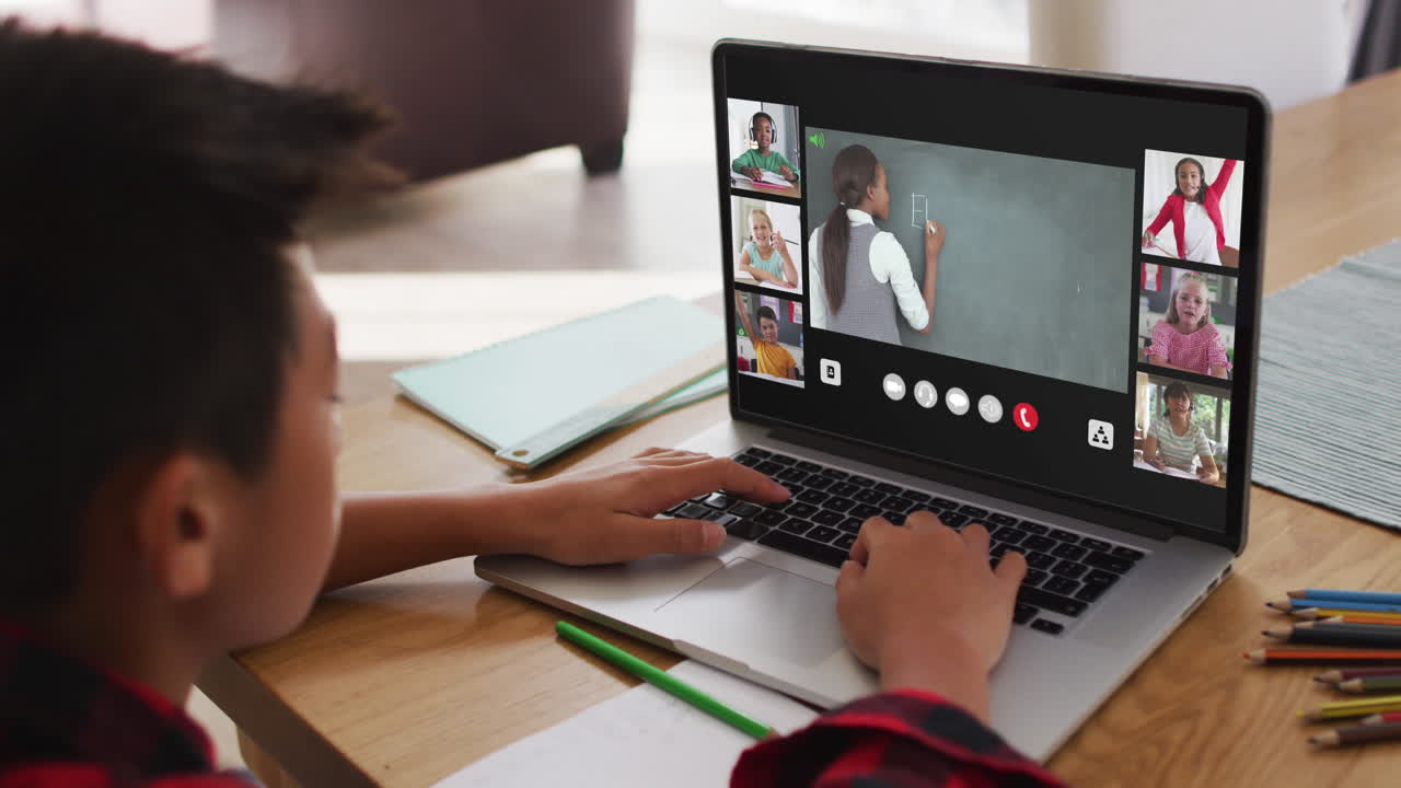 niño asiático teniendo una videoconferencia con el maestro y sus compañeros de clase en la computadora portátil en casa
