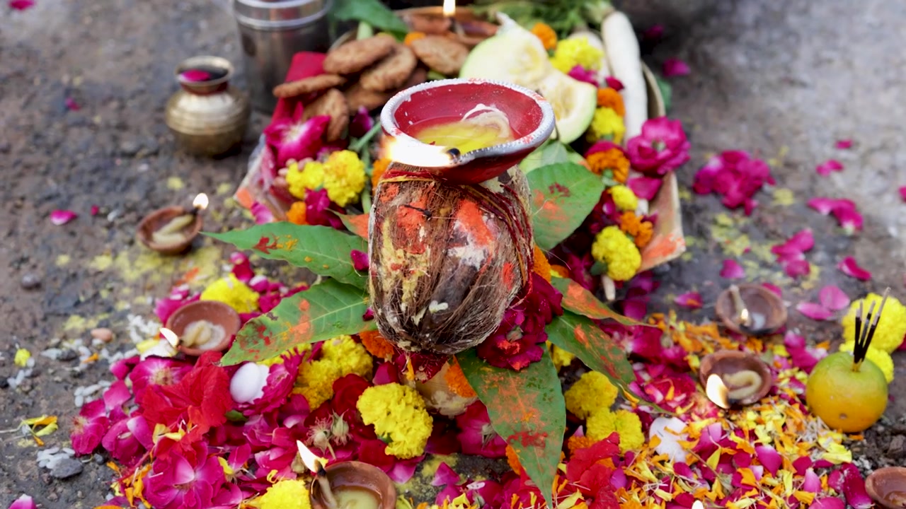 Allestimento rituale spirituale indù con diya illuminati, cocco e offerte floreali per il festival Chhath