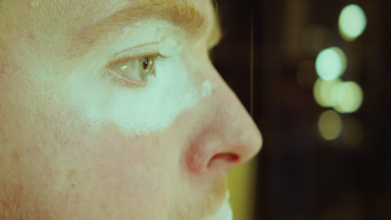 hombre aplicando maquillaje de payaso en el vestuario