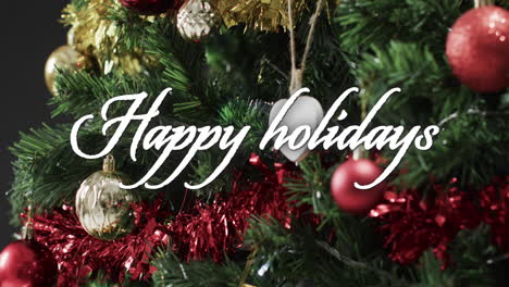 happy holidays text in white over decorations on christmas tree