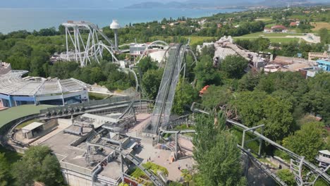 drone dolly above amusement park roller coaster tracks on beautiful italian day