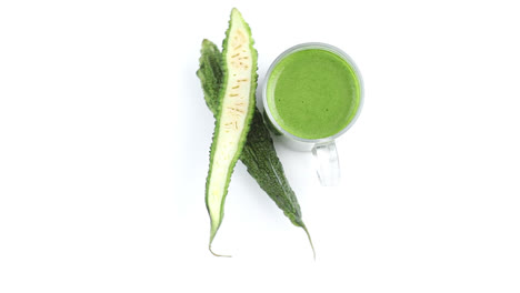 sliced-bitter-gourd-and-biter-gourd-juice,-paste-in-white-background-rotating-top-shot