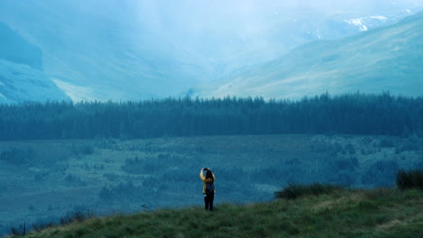 woman taking a photo of a scenic mountain valley