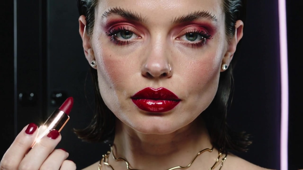 Applying female model pressing red lipstick while tube touching lip, showing final look in studio