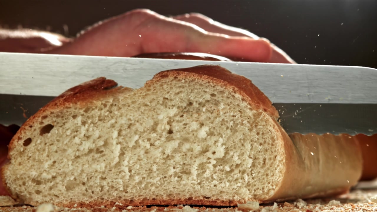 Close-up of a Fresh Loaf of Bread Being Sliced with a Knife
