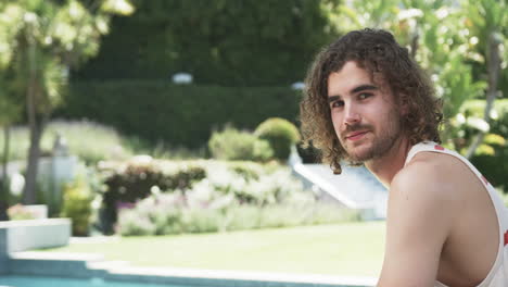 young caucasian man smiles by the poolside, with copy space